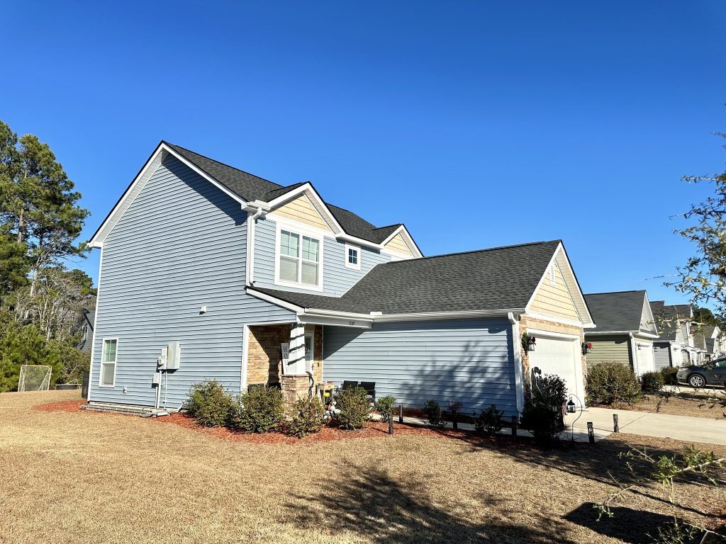 Two-story gray-blue home with a new dark shingle roof in Myrtle Beach, SC