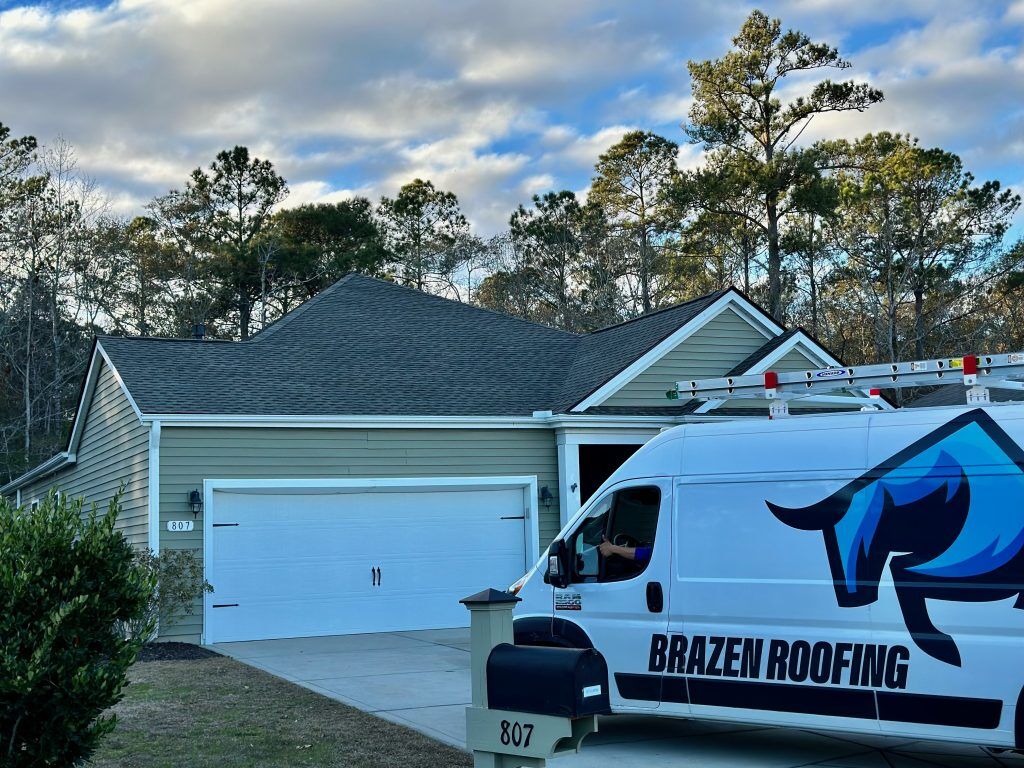 Close-up of a two-car garage roofline with a Brazen Roofing service van parked in the driveway in Myrtle Beach, SC