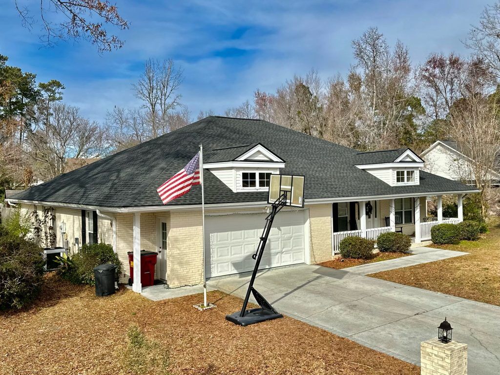 Tan two-story home with an American flag and ladder set up during a roof installation in Myrtle Beach, SC