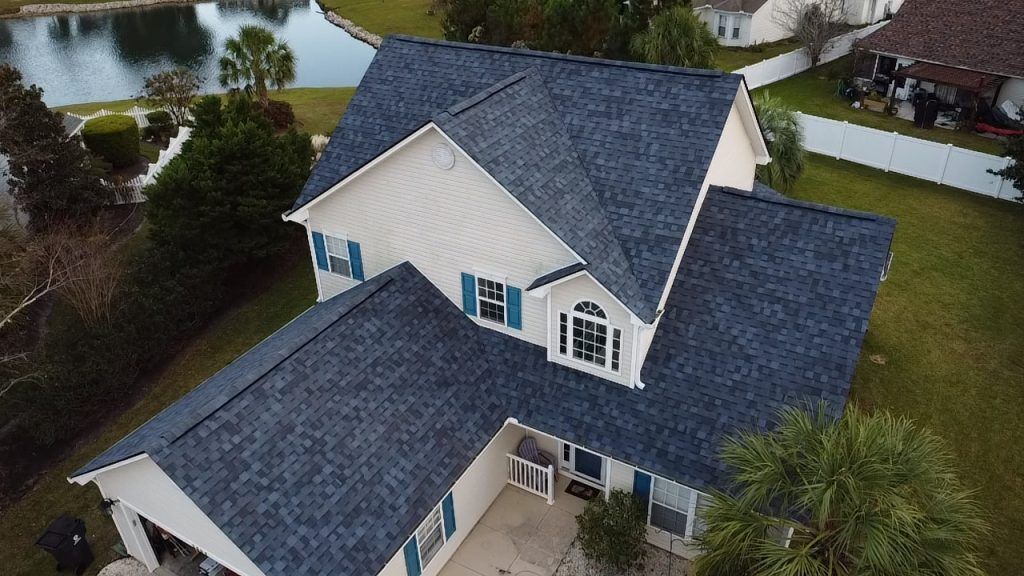 Aerial drone view of a completed gray shingle roof replacement on a waterfront home in Myrtle Beach, SC