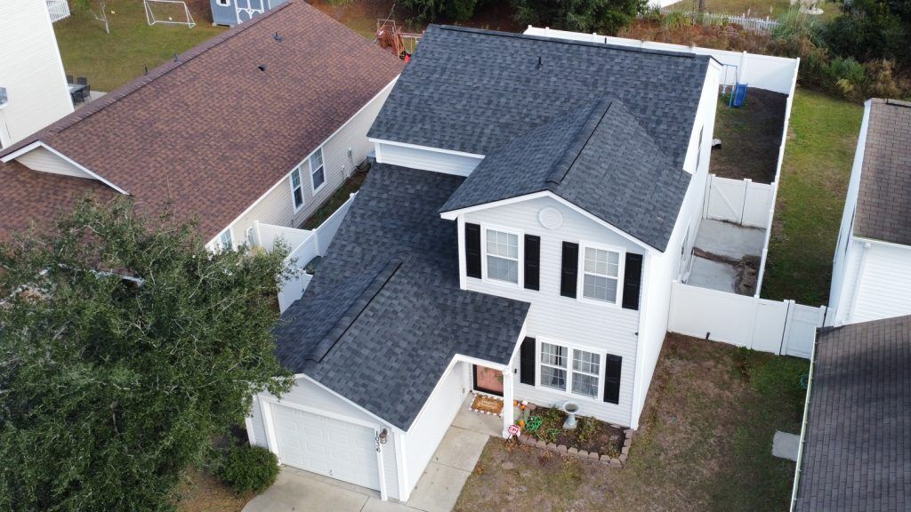 Aerial drone view of a completed shingle roof replacement surrounded by trees in Myrtle Beach, SC
