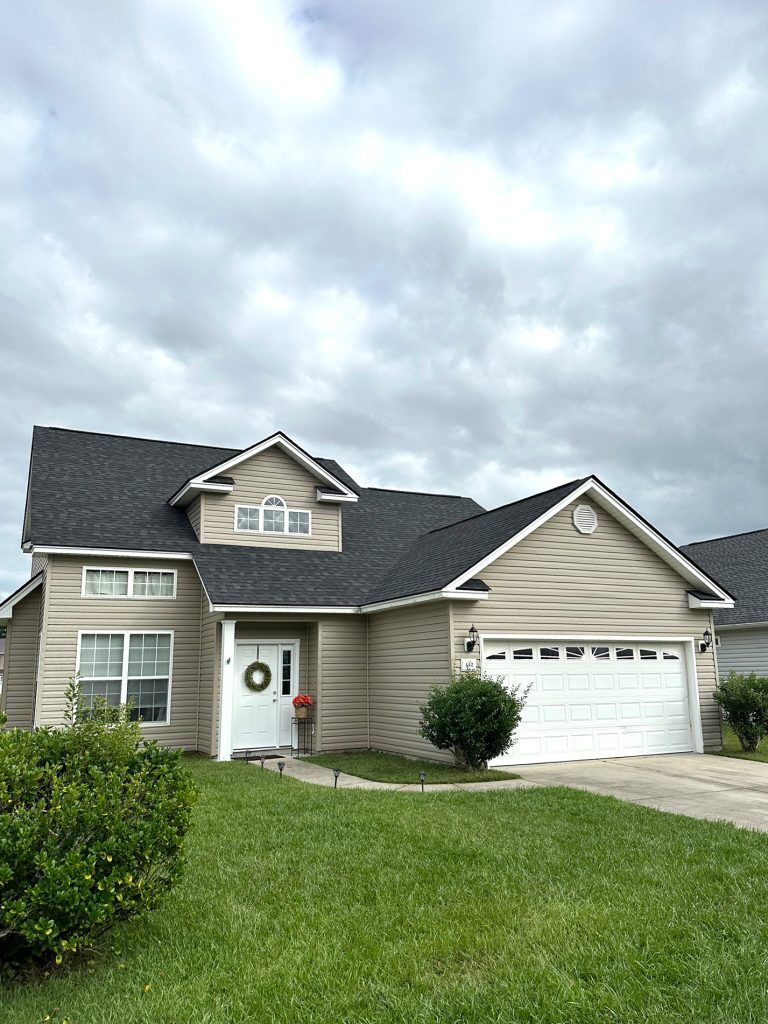 Two-story tan home with new dark gray shingle roof and attached garage in Myrtle Beach, SC
