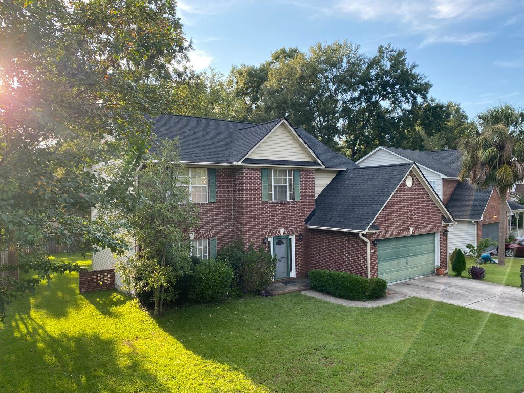 Two-story tan home with dormer windows and a newly installed shingle roof in Charleston, SC