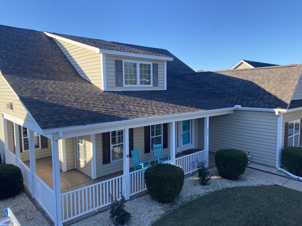 Tan two-story home with a covered porch and new shingle roof in Myrtle Beach, SC