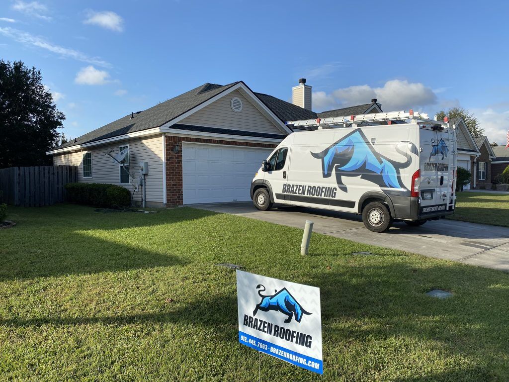 item_cad825dd-7bf1-4970-a4d6-73329fb1871a Tan single-story home with a Brazen Roofing service van and yard sign after a roof installation in Savannah, GA